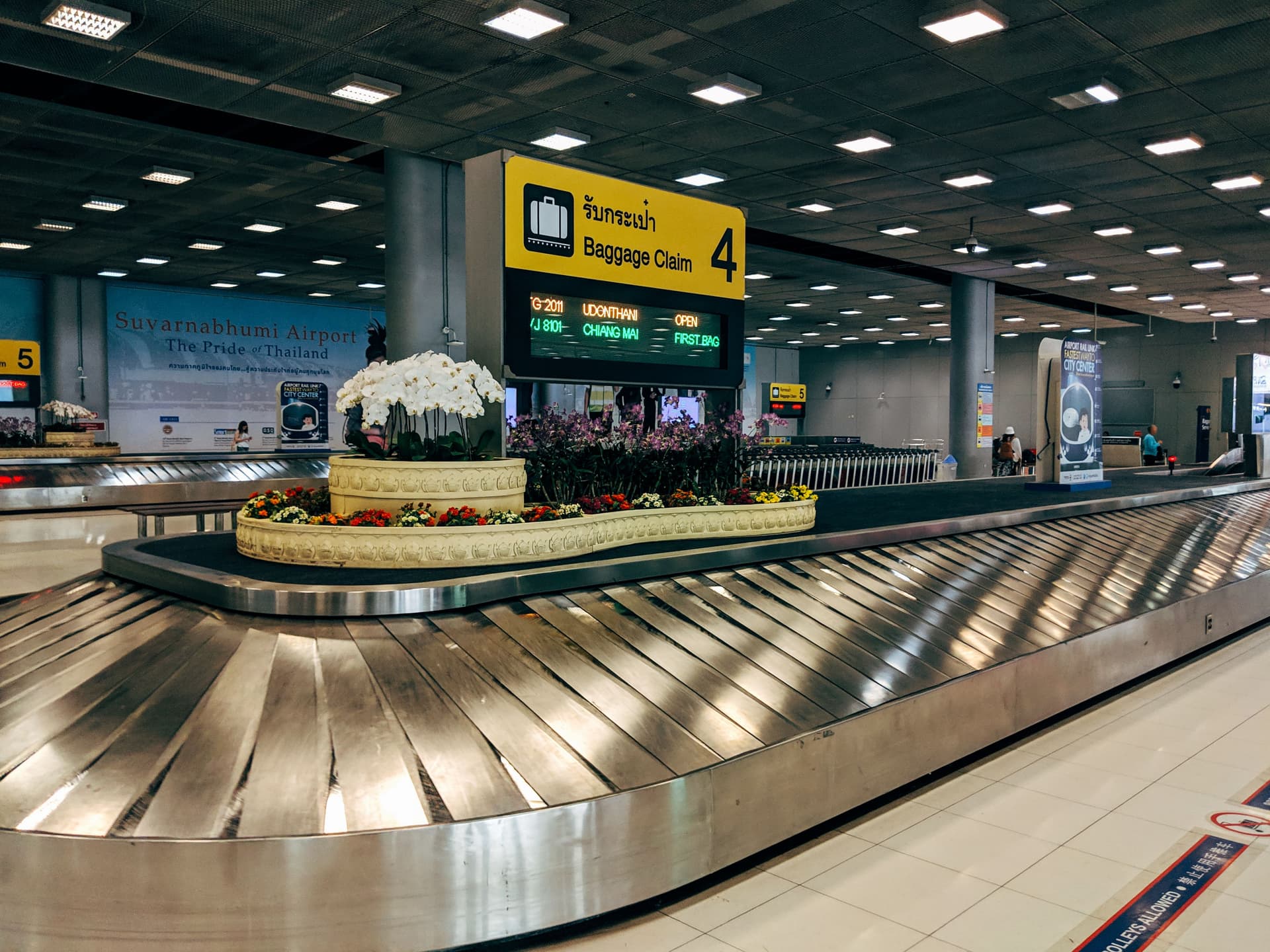 A baggage reclaim hall, with an empty carousel curving away under overhead signage.